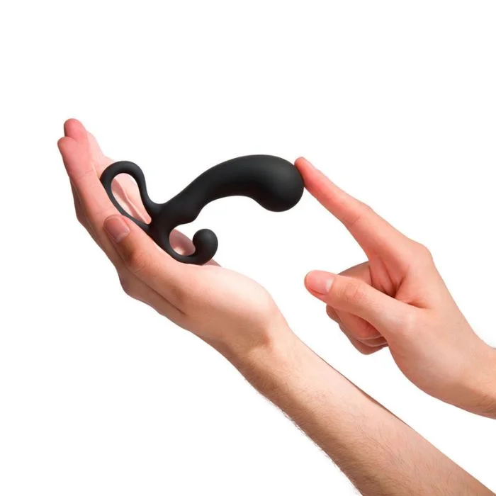 Χέρι κρατά μαύρο dildo για ερεθισμό του προστάτη σε λευκό φόντο.