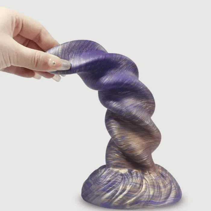 Χέρι με μακριά νύχια κρατά εύκαμπτο fantasy dildo με έντονες ραβδώσεις σε γκρι φόντο.
