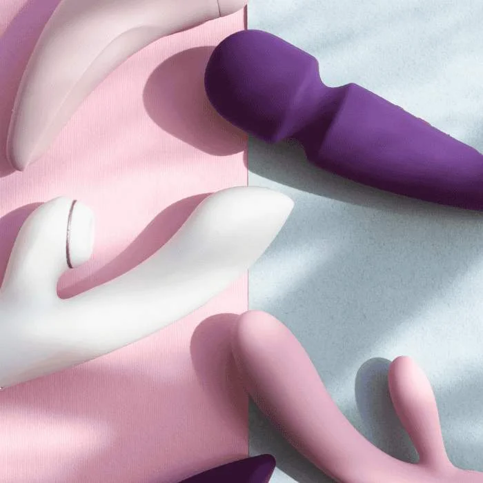 Διάφορα sex toys τοποθετημένα σε παστέλ φόντο με διαχωρισμό χρωμάτων και απαλό φωτισμό.