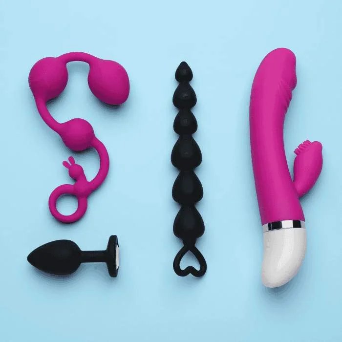 Διάφορα sex toys όπως rabbit δονητής, πρωκτικό βύσμα και σφήνες τοποθετημένα σε γαλάζιο φόντο.