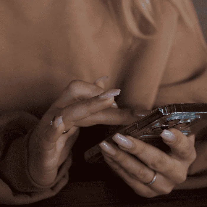 Γυναικεία χέρια κρατούν κινητό και πληκτρολογούν σε κοντινή λήψη.