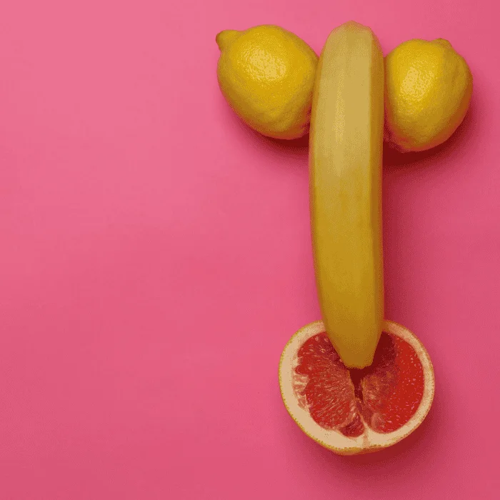 Δύο λεμόνια, μία μπανάνα και μισό γκρέιπφρουτ τοποθετημένα σε ροζ φόντο.