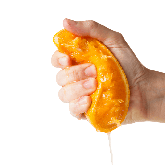 Χέρι που στίβει μισό πορτοκάλι πάνω σε λευκό φόντο.